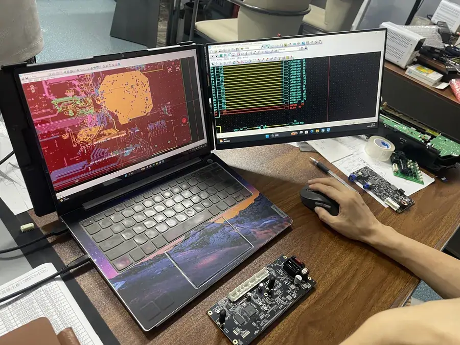 Engineers debugging a CarPlay decoder module on a dual-screen R&D bench
